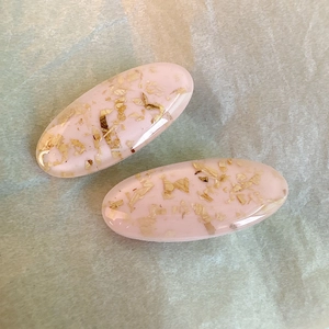 Coppia di fermagli per capelli ovali in resina rosa con foglie d'oro su fondo chiaro