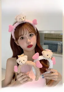 Détail de bandeau en peluche avec oreilles d'ours et ailes en rose, beige et blanc