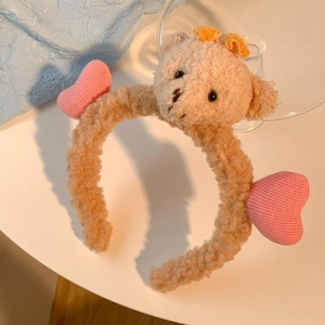 Détail d'un serre-tête en peluche ours brun avec nœud jaune et petits cœurs roses