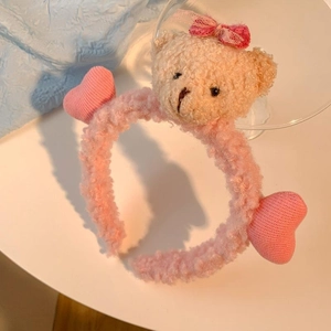 Détail d'un serre-tête rose en peluche avec petit ours et nœud en dentelle rouge