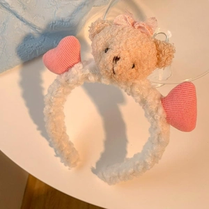 Détail d'un serre-tête en peluche blanche avec ours mignon, nœuds et cœurs roses