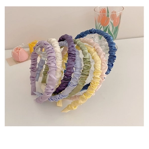Close-up of pleated satin headbands in various Morandi colors on a glass display