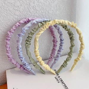 Detailed view of macaron colored pleated satin headbands with soft silk texture