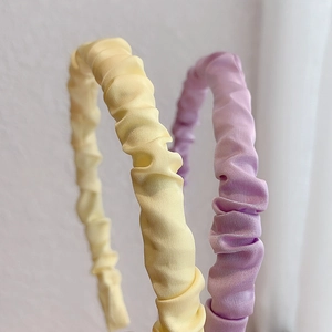 Detail of yellow and purple pleated satin headbands with soft silk texture and glossy finish