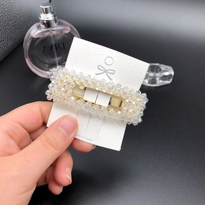 Detailansicht einer goldbeschichteten Haarspange mit weißen Kristallperlen auf Karte