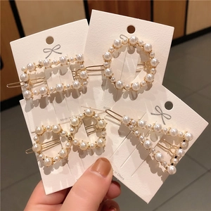Detail view of four assorted pearl hair clips in geometric shapes on white display cards