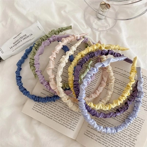 Chic satin pleated headbands in various pastel colors arranged on a white background