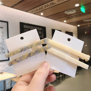 Close-up of marble texture and cream resin hair clips on a white display card