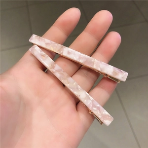 Detailed close-up of pink marble pattern acetate hair clips with golden metal base