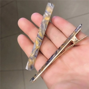 Close-up of marble pattern acetate clip and golden metal duckbill hair clip set