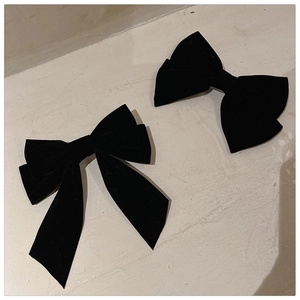 Detail of two black velvet bow hair clips with elegant long ribbons and French retro style