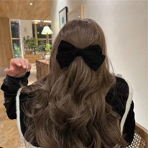 Detail showing a large black velvet bow hair clip styled on long wavy hair