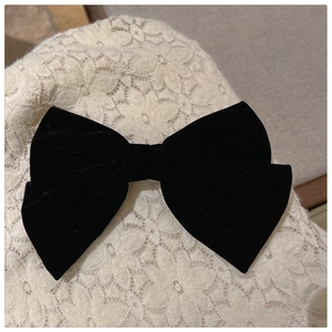 Close-up of black velvet bow hair clip with luxury texture on white lace background