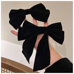 Close-up of black velvet bow hair clips with long ribbons showing elegant fabric texture
