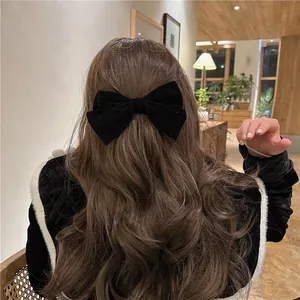 Elegant large black velvet bow hair clip worn by a woman with long wavy brown hair