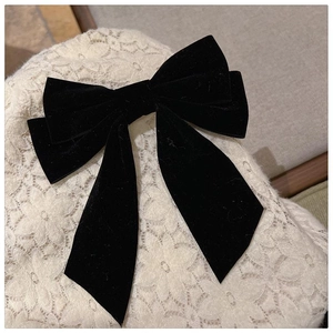 Elegant black velvet bow hair clip with long ribbons on a white lace background