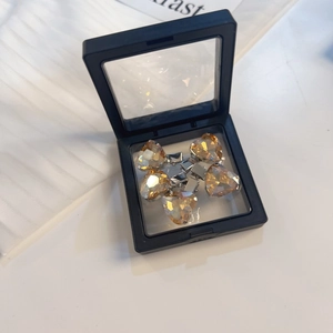 Detail van vijf champagne hartvormige kristallen clips in een zwarte PE-folie doos