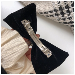 Detail of silver metal spring clip with Paris engraving on black velvet bow hair clip