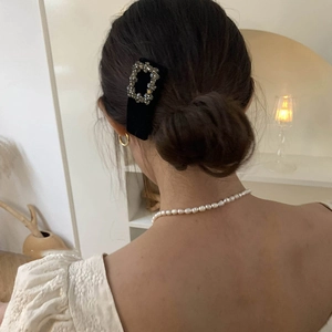 Detail of a large black velvet baroque hair clip with square crystal buckle on a model