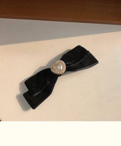 Detail of vintage black velvet bow hair clip with a central heart-shaped pearl accent