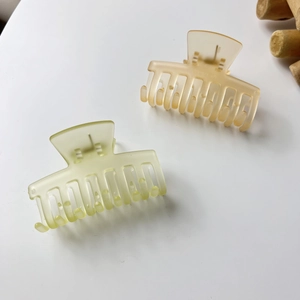 Matte jelly hair claw clips in pale lemon yellow and peach pink showing multi-tooth grip