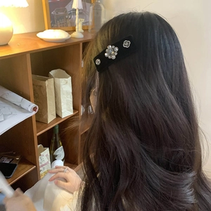 Detail view of large baroque black velvet hair clip with crystals on wavy hair