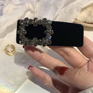 Close-up of black velvet hair clip featuring a sparkling rectangular rhinestone buckle