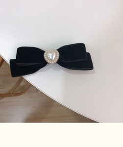 Close-up of black velvet bow hair clip with a heart pearl centerpiece and beaded edges