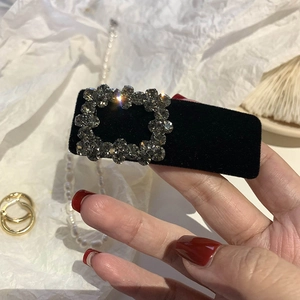 Close-up of black velvet hair clip featuring a luxury square crystal buckle detail