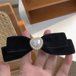 Detail of vintage black velvet bow hair clip with heart-shaped pearl centerpiece