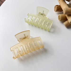 Detail of matte jelly hair claw clips in pale green and amber resin with wood decor