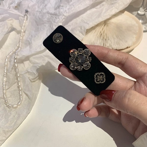Macro detail of black velvet hair clip with elegant crystal flower and diamond ornaments