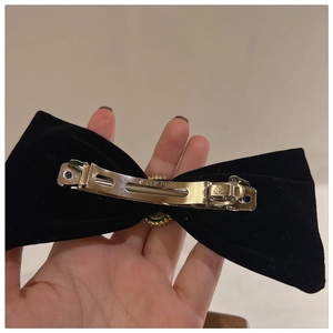 Detailed close-up of the silver metal spring clip on a black velvet bow hair clip