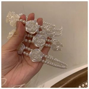 Close-up of elegant double-row pearl headbands featuring white resin rose ornaments