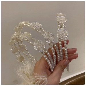 Detail of elegant white resin rose and faux pearl double-strand headband for women