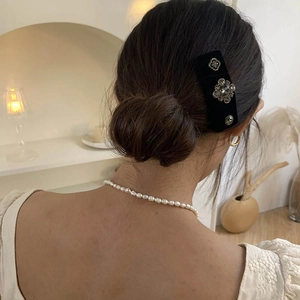 Baroque black velvet hair clip with crystals on a woman's hair in an elegant home setting