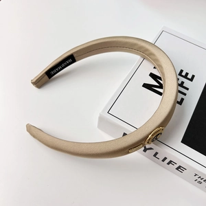 Detailed macro view of champagne gold satin headband with vintage metal emblem decoration