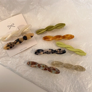 Close-up of twisted acetate hair clips in tortoiseshell and marble patterns on white card