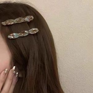 Detail showing two twist pattern acetate hair clips worn on brunette hair