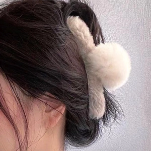 Gros plan sur la pince à cheveux en fausse fourrure douce de couleur blanc crème