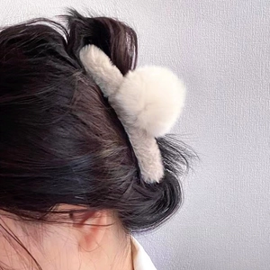 Détail d'une pince à cheveux en fausse fourrure gris clair sur un chignon élégant