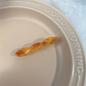 Close-up of tortoise shell acetate hair clip showing the smooth twist texture on beige tray