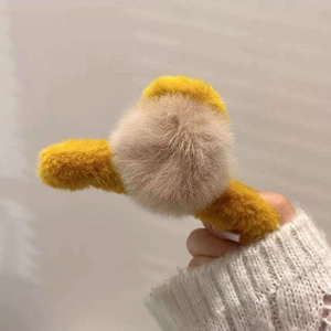 Détail d'une pince à cheveux en fausse fourrure jaune et beige pour coiffures d'hiver
