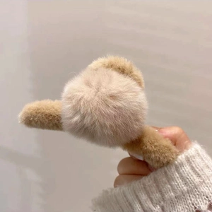 Détail de la pince à cheveux en peluche camel avec un pompon doux et volumineux