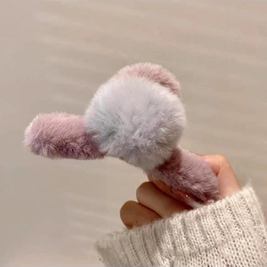 Gros plan d'une pince à cheveux en fausse fourrure douce mauve et beige pour l'automne