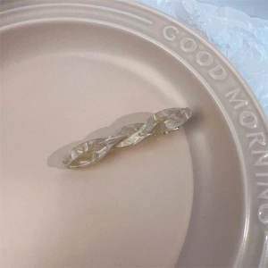 Macro detail of elegant marble-textured acetate hair clip on ceramic plate