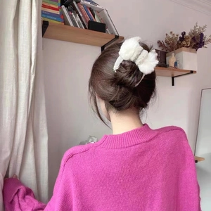 Gros plan d'une pince à cheveux en peluche blanche avec nœud portée sur un chignon