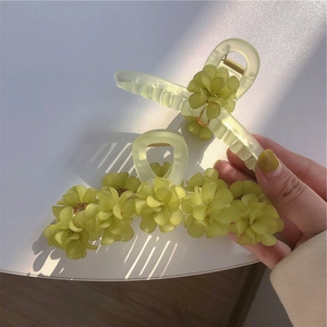 Détail des pinces à cheveux vert forêt avec fleurs de muguet et fini translucide