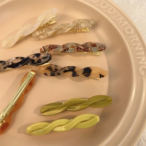 Detailed macro view of assorted resin twist hair clips with marble patterns on ceramic tray