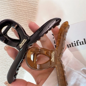Vue détaillée de grandes pinces à cheveux ambre et noires avec inscription dorée élégante